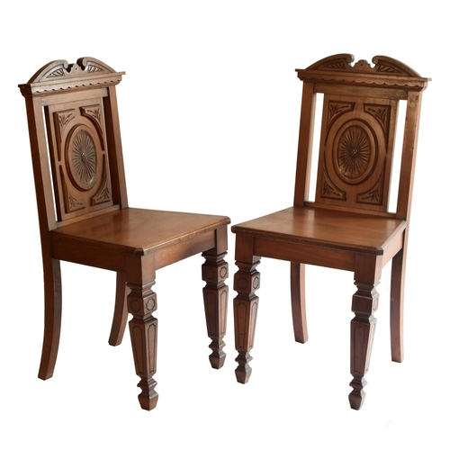 1681 - Pair of late 19th century walnut hall chairs, the carved panel backs with oval motifs upon solid sea... 