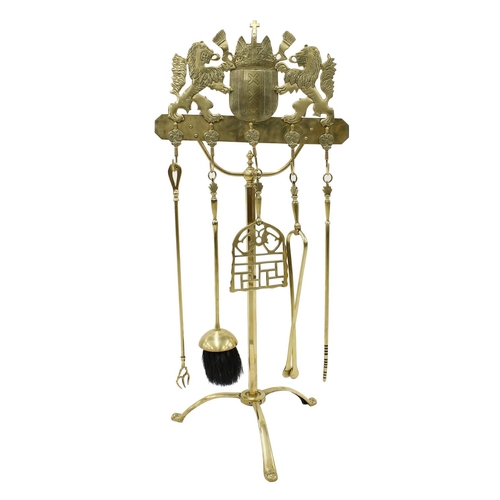 1124 - Decorative polished brass fireside companion set, the stand surmounted with a heraldic Coat of Arms,... 