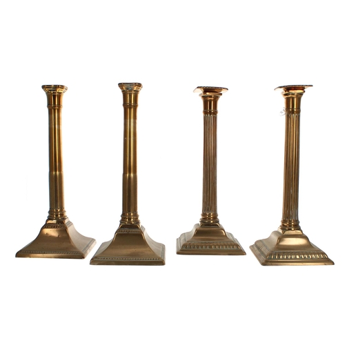 1052 - Pair of Georgian Corinthian column brass candlesticks, with plain reeded columns upon square bases, ... 