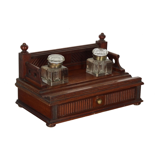 1066 - Edwardian oak desk inkstand, the gallery back inset with a pair of square glass inkwells over a sing... 