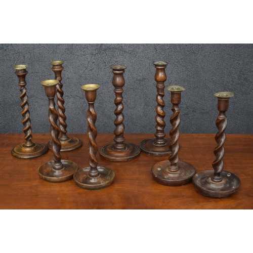 1083 - Four pairs of antique oak barley twist candlesticks, all with brass or copper sconces, tallest pair ... 