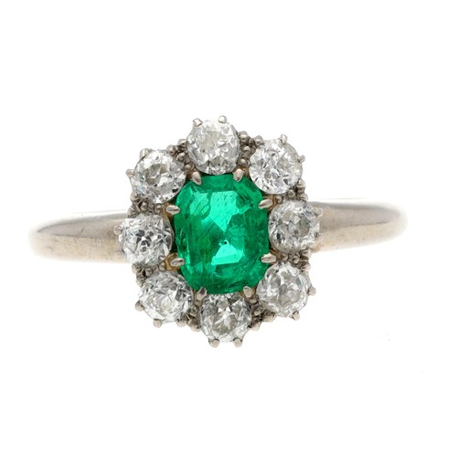 56 - Attractive period emerald and diamond white metal cluster ring, the emerald 0.60ct approx, in a surr... 