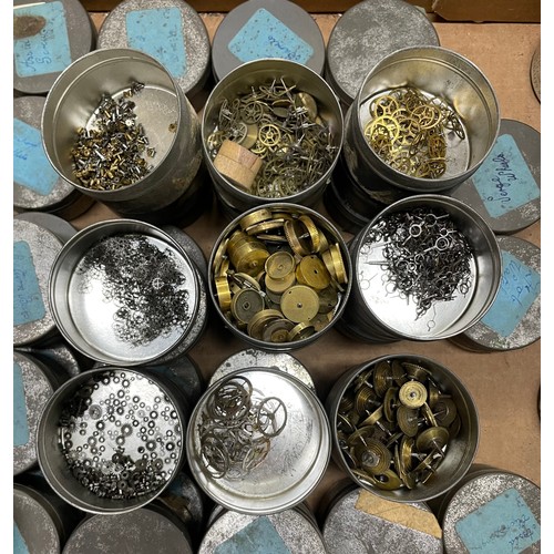 261 - Quantity of watch parts contained within metal tins including verge wheels, barrel bridges, jewels, ... 