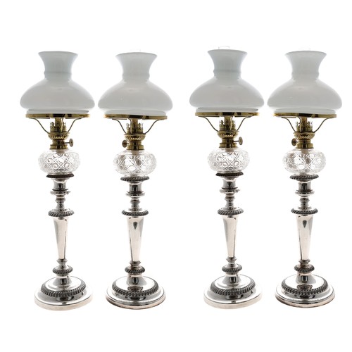 Good set of four silver plated copper candlesticks converted to oil lamps, each with cut glass reservoir, clear glass chimney and opaque glass shade, upon cylindrical tapered bodies with wrythen decoration and circular bases, 21.5” high approx