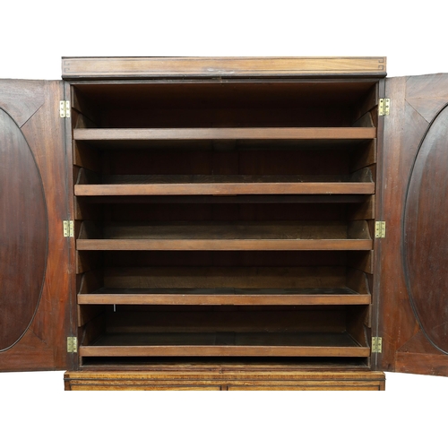 772 - Early 19th century flamed mahogany linen press, the cornice over an upper of two oval panelled doors... 