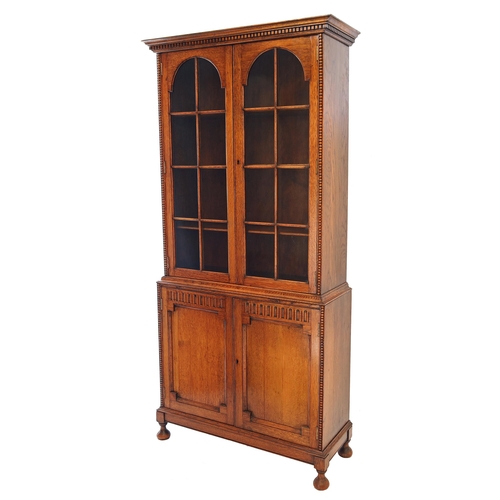 809 - 1930s tall oak glazed bookcase, the upper with with key border cornice over two arched astragal glaz... 