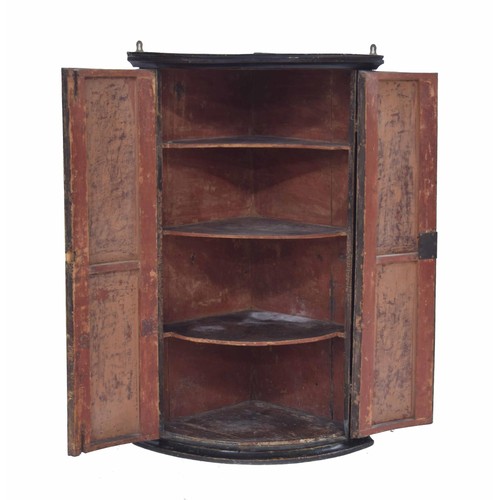 952 - Georgian painted bow-front hanging corner cupboard, the two hinged doors decorated with a religious ... 