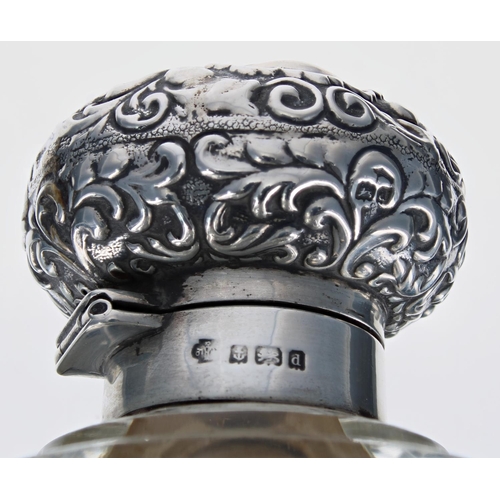 1172 - Edwardian silver mounted glass globe scent bottle, the repousse hinged cover enclosing an inner glas... 