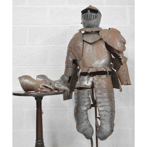 Victorian part suit of armour in the medieval style, with close helm helmet, collar, rivet construction chest and back plates, arms with gloves and thigh armour (lacking any boots and with missing rivets/broken leather straps various etc.); also with an armorial shield