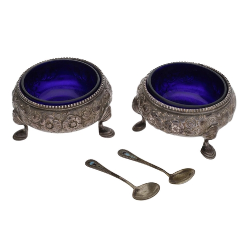 409 - Pair of Victorian silver circular salts, ornate floral embossed decoration on pad feet, blue glass l... 