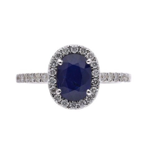 25 - Modern white gold oval sapphire and diamond cluster ring with diamond set shoulders, the oval sapphi... 