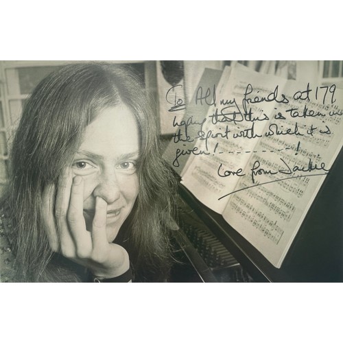 A photograph - Jacqueline du Pré, posing by the piano, resting her head on her hand and looking at the camera, her little finger up her nose, inscribed by Jackie "To All my friends at 179, hoping that this is taken in the spirit with which it is given!........! Love from Jackie"