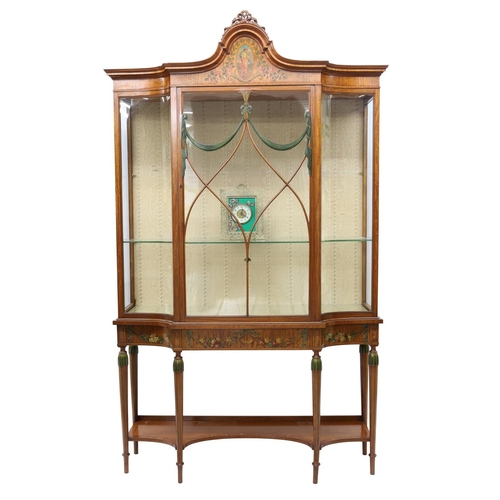 Good Edwardian satinwood, inlaid and painted display cabinet, the arched top with ribbon cresting and an oval painted portrait panel of a lady within a floral surround, the astragal glaze door with swag ornament flanked by a concave  glass panel to either side, fitted with plate glass shelves, the frieze decorated with further swags of roses on turned and tapered legs joined by a concave under tier, 49" wide, 16" deep, 81" high