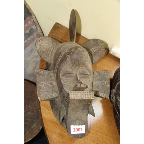 2002 - African: a tribal carved wood mask, of stylised form; together with a wooden club. (2)