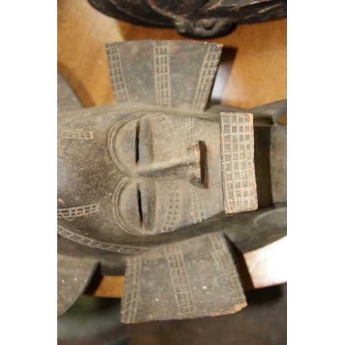 2002 - African: a tribal carved wood mask, of stylised form; together with a wooden club. (2)