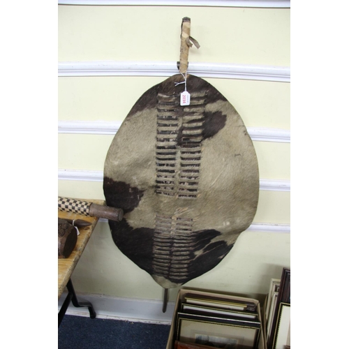 2034 - African: a South African Zulu spotted cowhide shield, with wooden pole, total length 129.5cm.