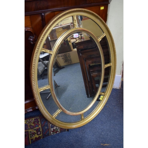 1928 - A gilt gesso framed oval wall mirror, with margin frame, 94 x 73.5cm.