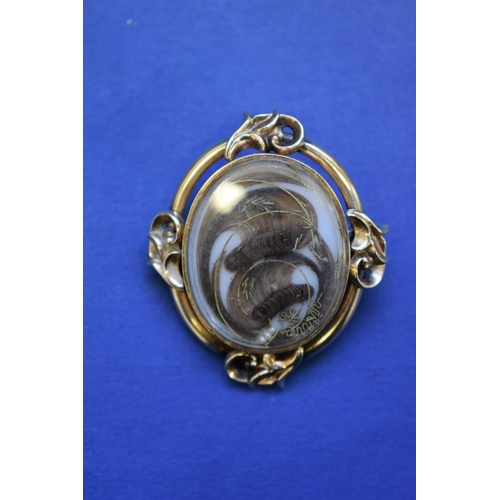 82 - A Victorian unmarked gold memento mori brooch, having coiled hair, gold thread and pearl decoration ... 