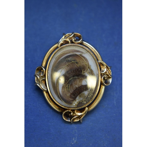 82 - A Victorian unmarked gold memento mori brooch, having coiled hair, gold thread and pearl decoration ... 