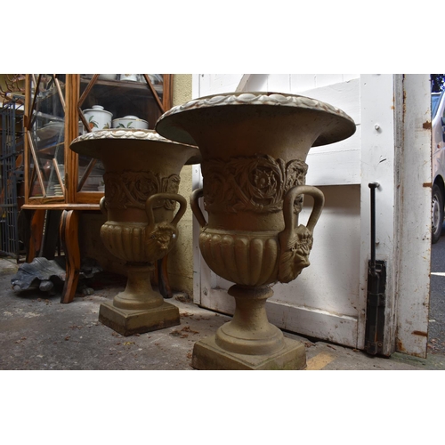 1280 - A pair of painted cast iron twin handled garden urns, 62cm high.