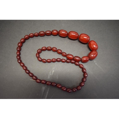 188 - A string of graduated cherry red amber style beads, 74cm, 68g.