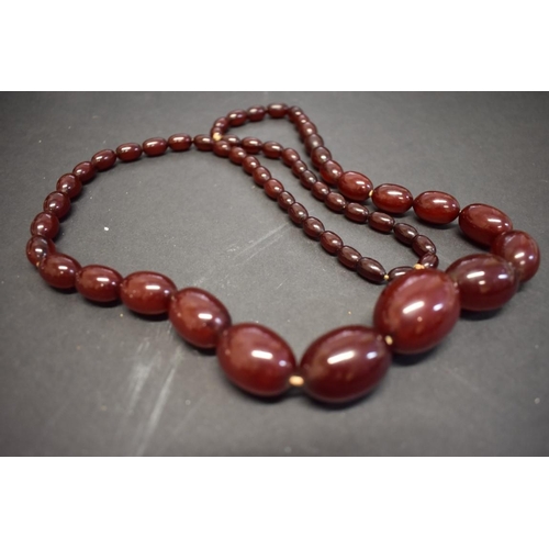 196 - A string of graduated dark cherry amber style beads, 96cm, 114g.