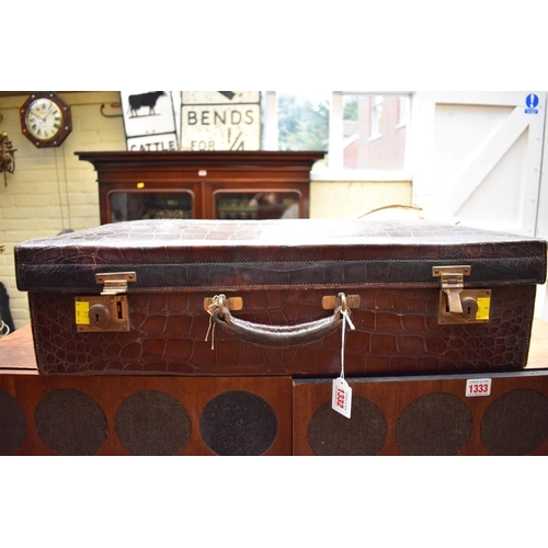 1332 - A vintage crocodile suitcase, inscribed 'Finnigans...', 62.5cm wide.