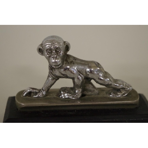 568 - Two car mascots, comprising: a centurion head, 11cm high; and a chimpanzee, 8cm wide. (2)... 