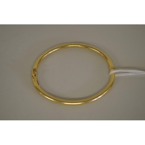 94 - A gold hinged bangle stamped 750, 7.9g.