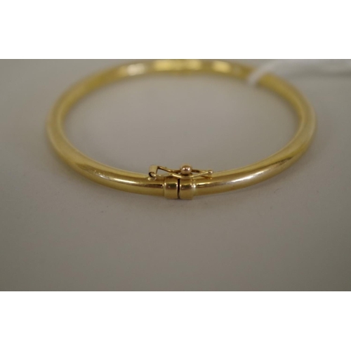 94 - A gold hinged bangle stamped 750, 7.9g.