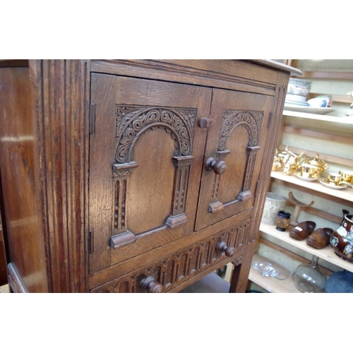 1194 - A reproduction carved oak small cupboard, 69cm wide. 