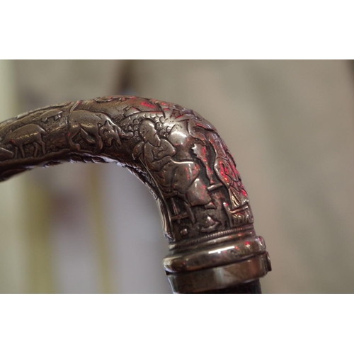 1743 - An eastern silver mounted ebony walking stick, the handle relief decorated with figures and ani... 