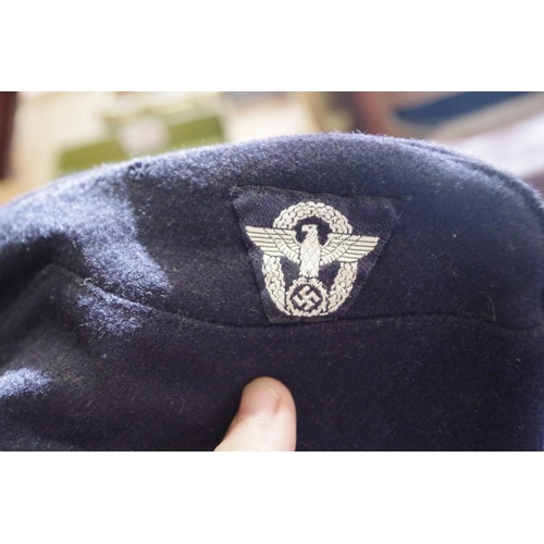 1756 - A German Third Reich navy blue felt overseas police side cap, with cloth badge.... 