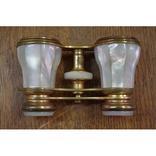 1766 - A cased pair of mother-of-pearl and gilt brass opera glasses.