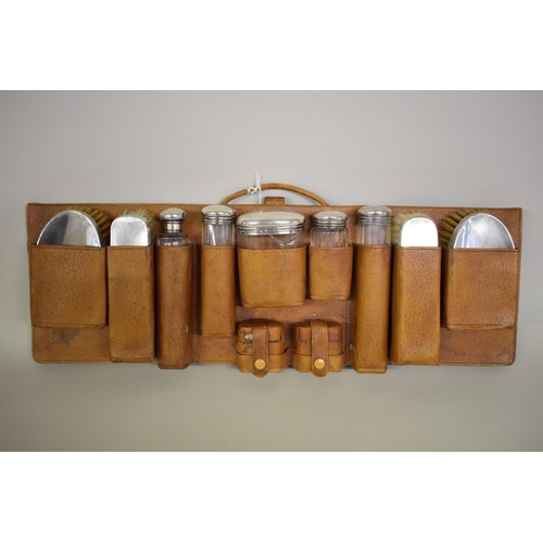 81 - A vintage hanging leather cased set of silver mounted bottles and brushes, different makers and date... 