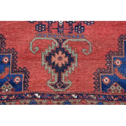 1132 - A Persian rug, having central medallion with urn design on a red ground with floral and geometr... 