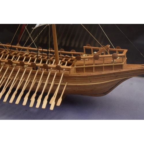 1215 - A wood model of a ancient Greek bireme, 49cm long, in glass case. 