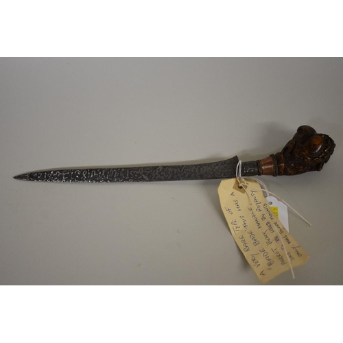 1720 - An Indonesian bade bade knife, having 23cm script inscribed blade, with carved wood parrot head pomm... 