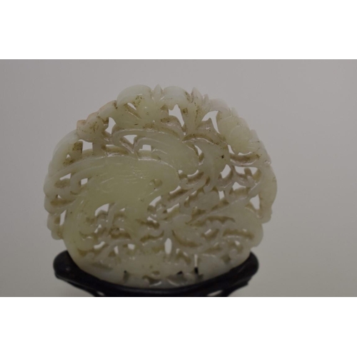 558 - A Chinese carved and pierced celadon jade roundel, decorated with a phoenix, 7.5cm diameter, on carv... 