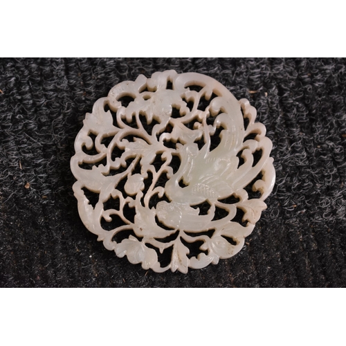 558 - A Chinese carved and pierced celadon jade roundel, decorated with a phoenix, 7.5cm diameter, on carv... 