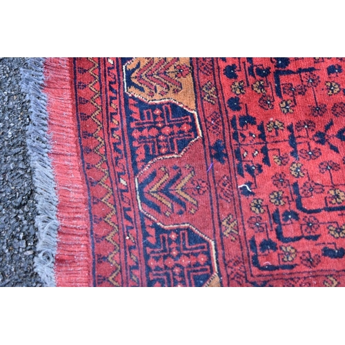 1123 - An Eastern rug, having repeated medallions to central field with geometric borders on a red ground; ... 