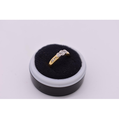 98 - A triple diamond collet set gold ring, hallmarked 750, having diamond chip shoulders, 3.1g total wei... 