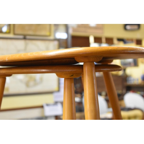 1757 - A vintage Ercol 'Blonde' circular low occasional table, 98cm long; together with a nest of two Ercol... 