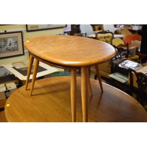 1757 - A vintage Ercol 'Blonde' circular low occasional table, 98cm long; together with a nest of two Ercol... 