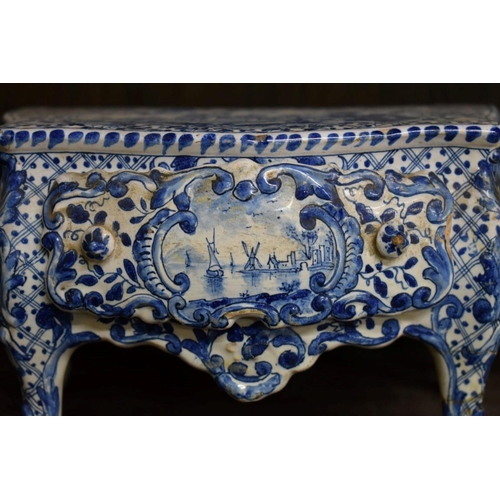 1554 - A Delft miniature commode, 18cm wide; together with another similar cow, 20cm long, (both s.d.).... 