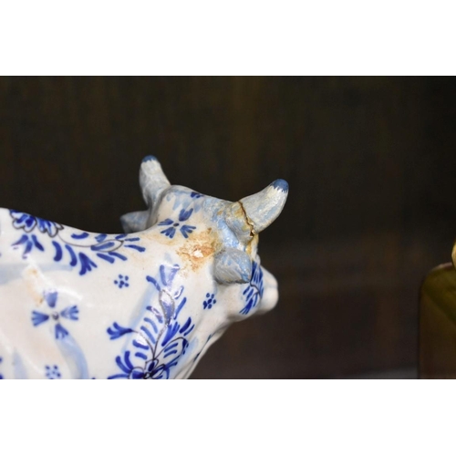 1554 - A Delft miniature commode, 18cm wide; together with another similar cow, 20cm long, (both s.d.).... 