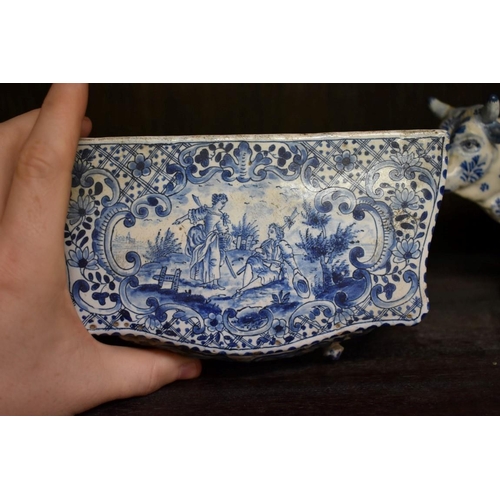 1554 - A Delft miniature commode, 18cm wide; together with another similar cow, 20cm long, (both s.d.).... 