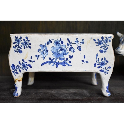 1554 - A Delft miniature commode, 18cm wide; together with another similar cow, 20cm long, (both s.d.).... 