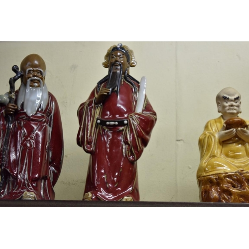 1589 - A set of three Chinese stoneware figures of immortals, each with impressed mark, largest 31cm high; ... 