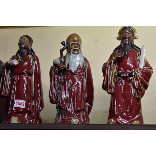 1589 - A set of three Chinese stoneware figures of immortals, each with impressed mark, largest 31cm high; ... 